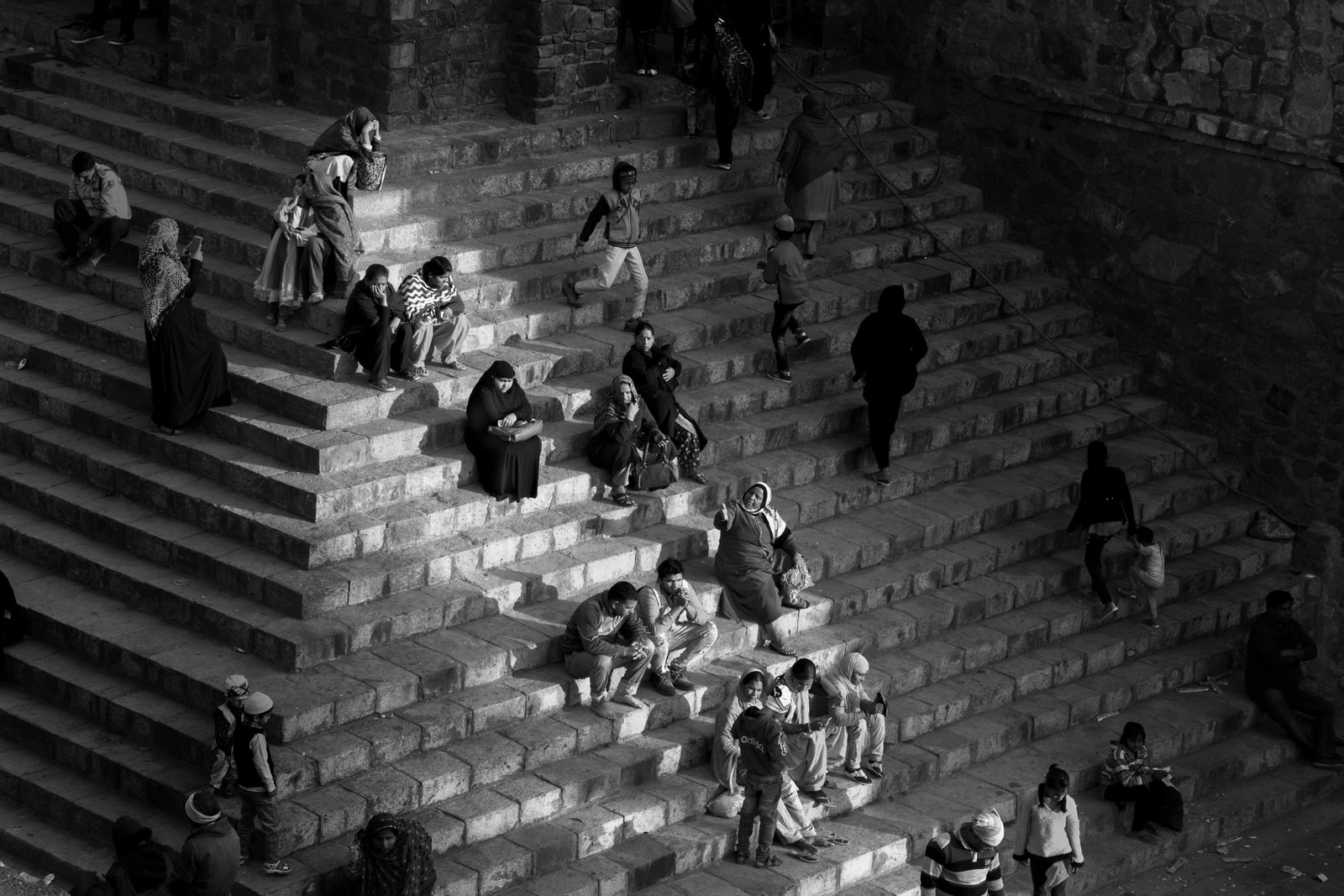 Photograph by Taha Ahmad: people seated across a stepped stone structure